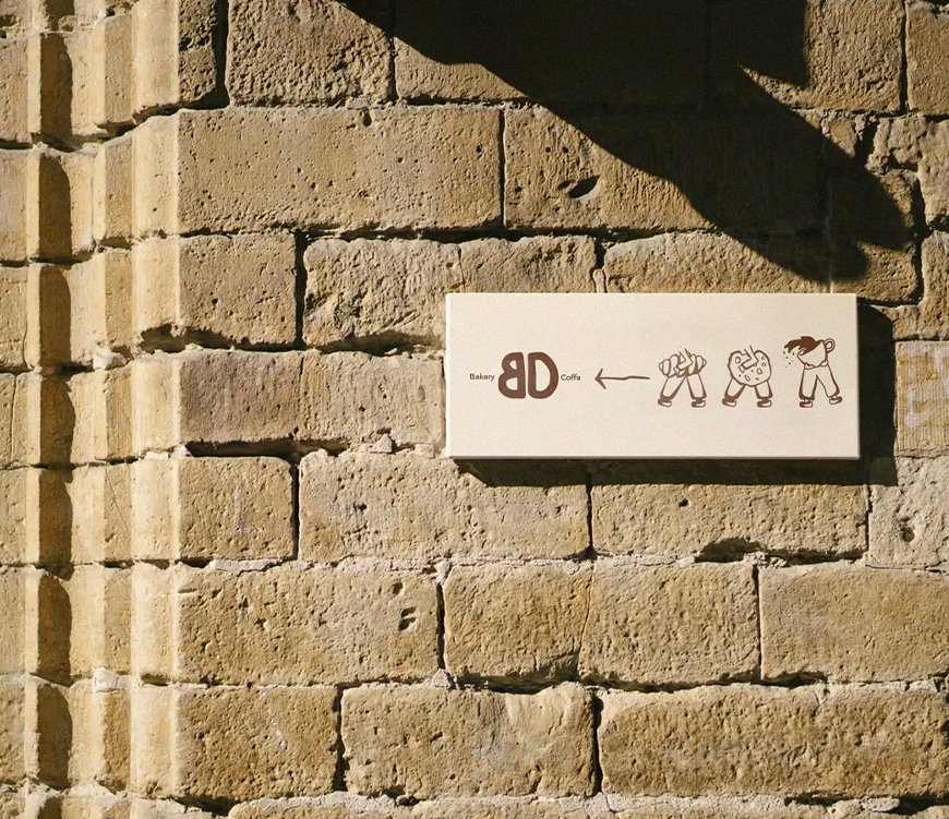 Bakerdays bakery identity displayed on a sunlit stone wall